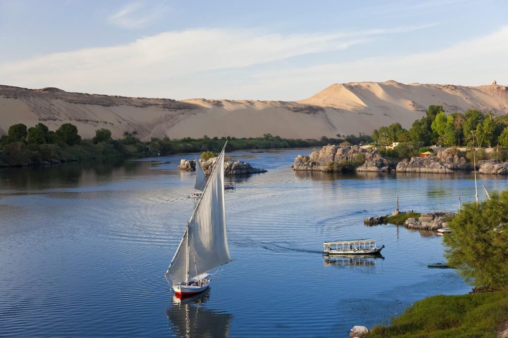 High angle view of sailboats on a river, sand hills in the distance.